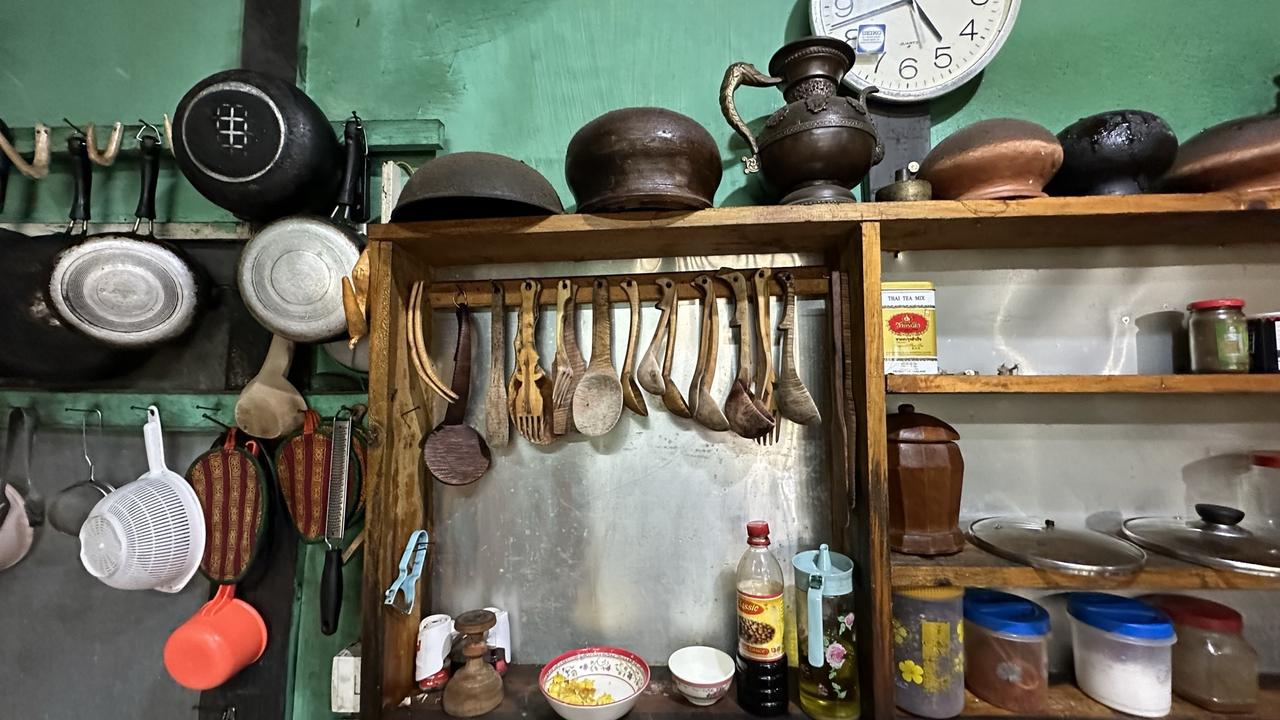 Pans and equipment hanging against a green kitchen wall at a Bhutan farmstay