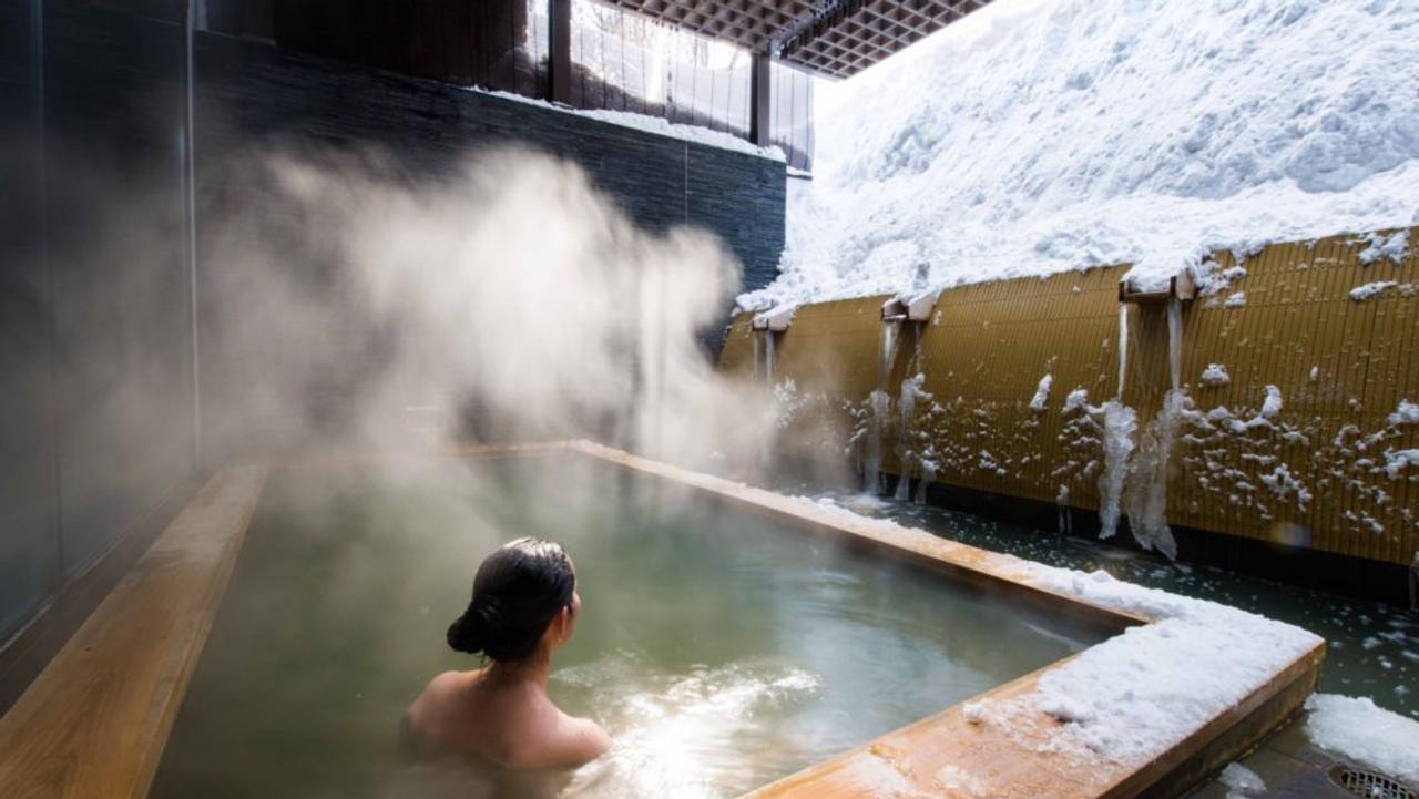 Woman relaxing in an onsen bath in Japan, half-open to the air, with snow on the surrounding ground. Selective Asia.