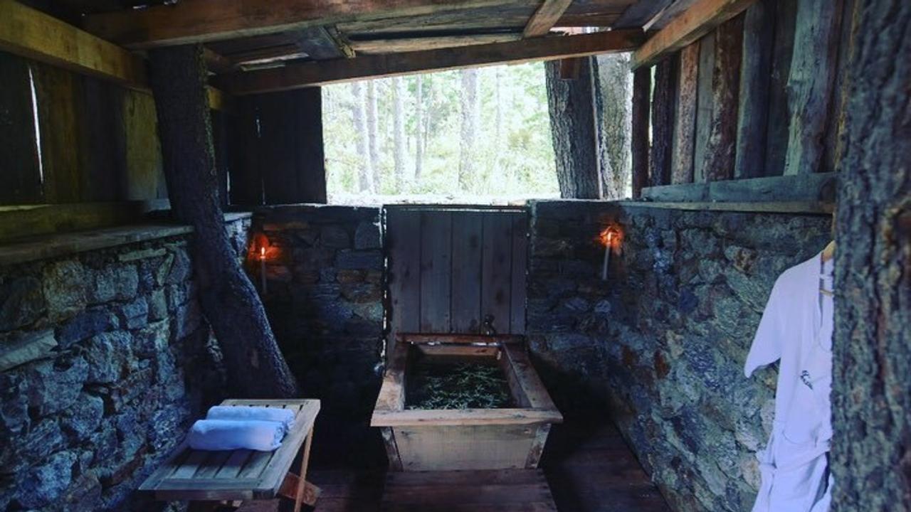 Small stone-lined bathroom with a traditional wooden hot stone tub against the far wall